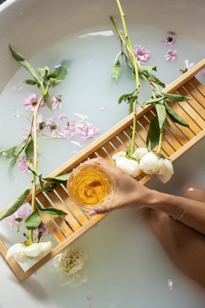 woman holding glass with wine while taking bath
