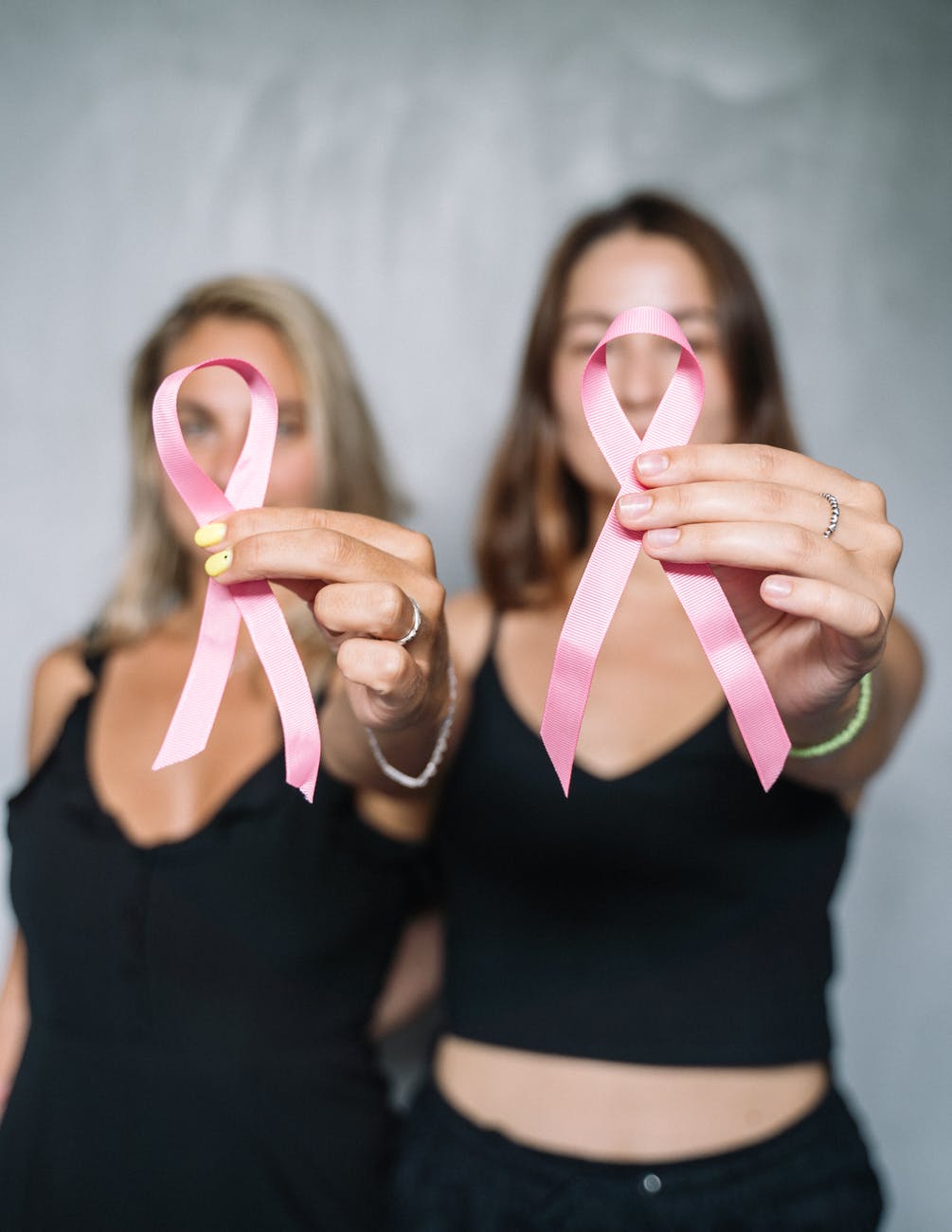 women in black tank top holding pink ribbons