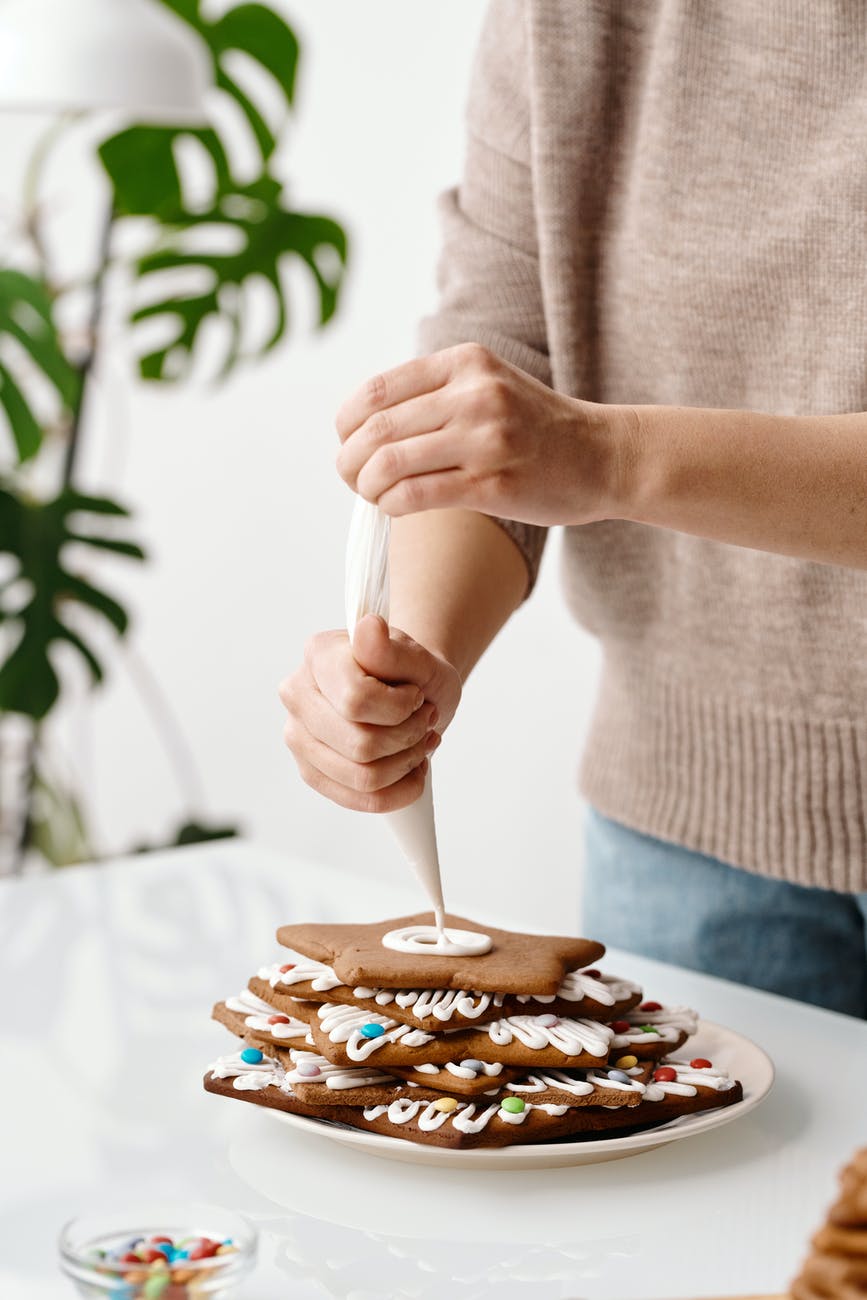a person putting whipped cream on top of the cookies