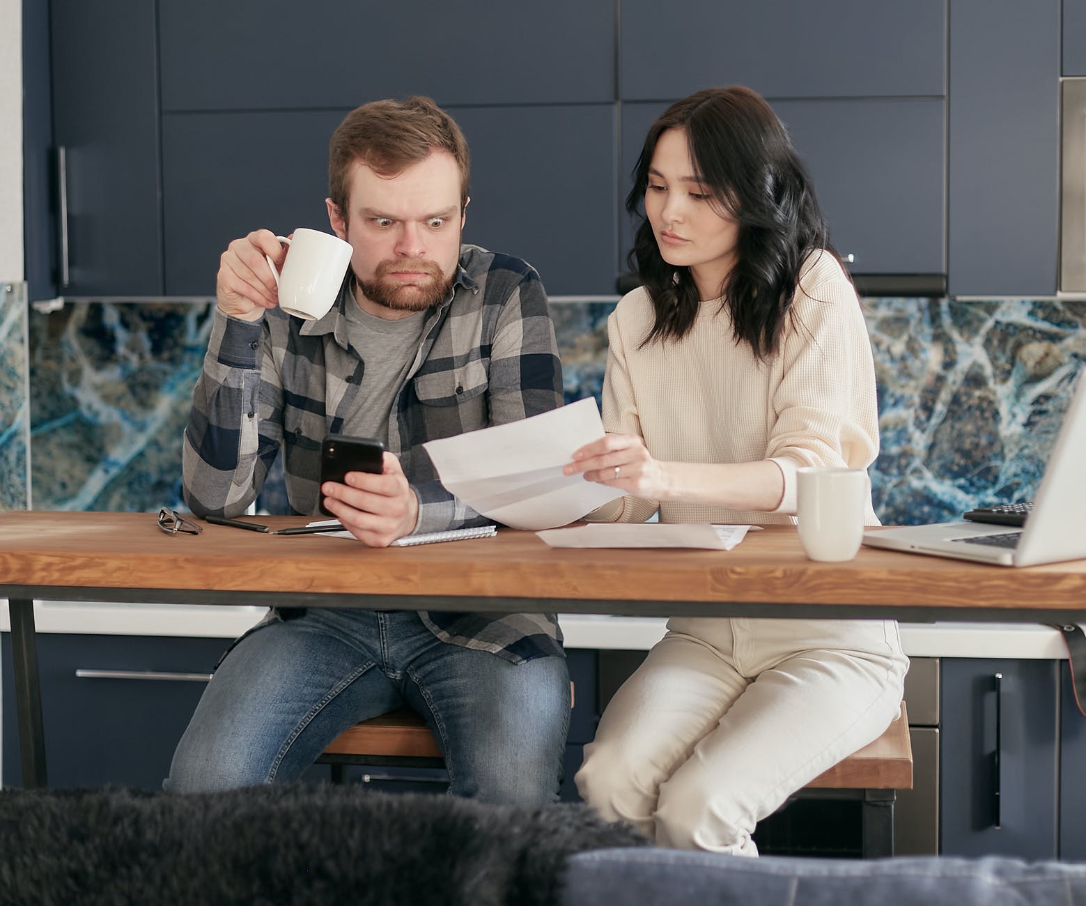 a man looking at the paper while holding a coffee and phone