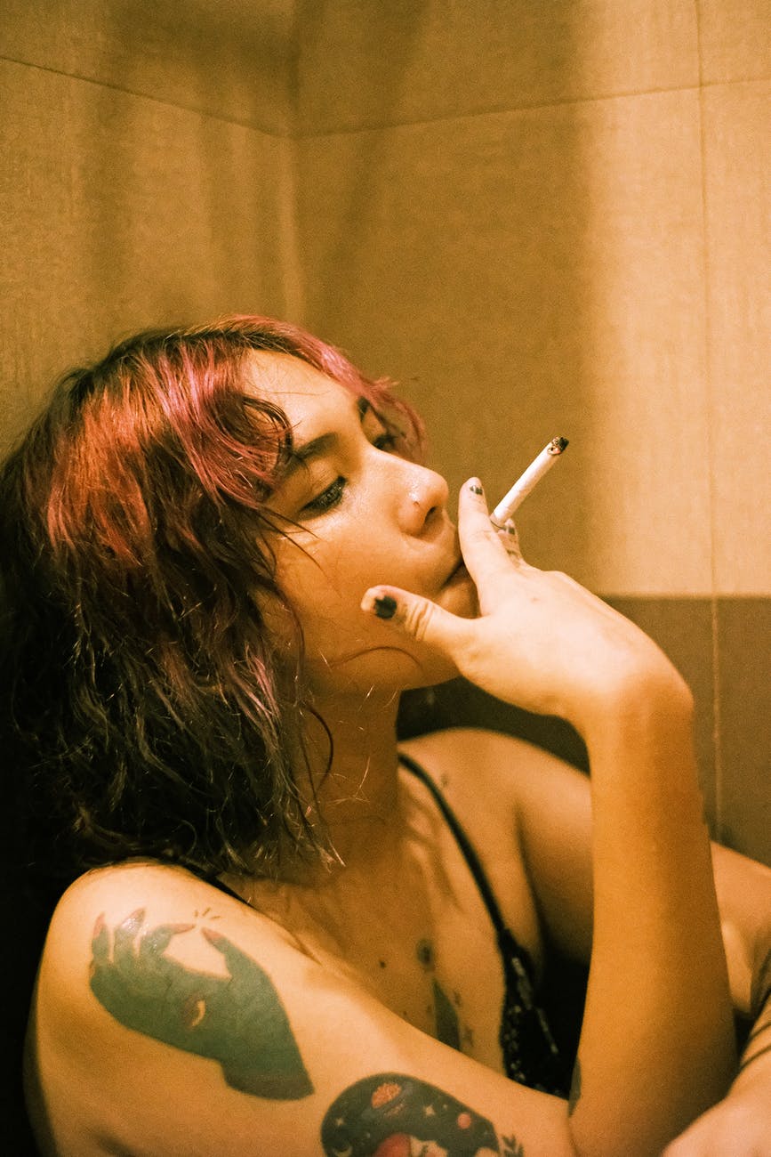 woman smoking while leaning on wall