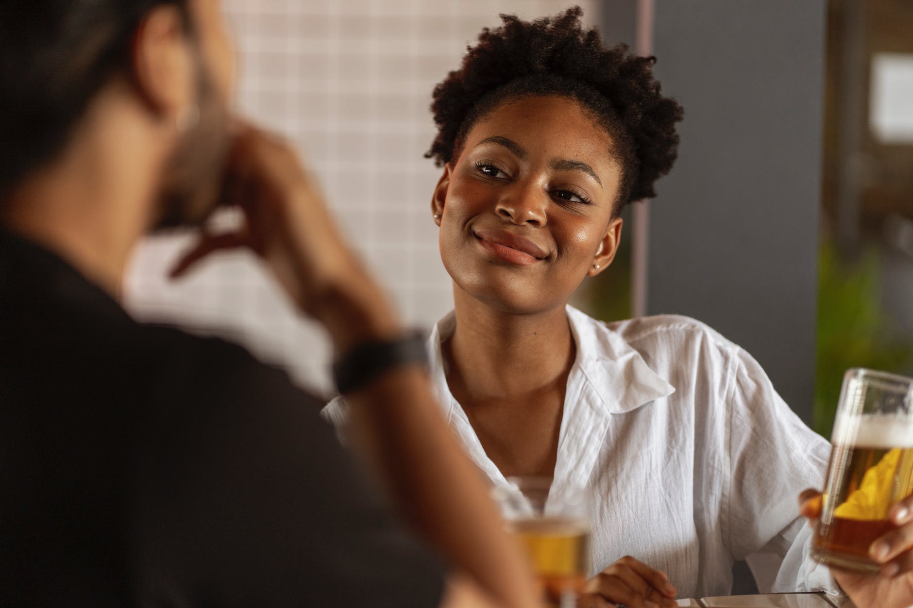 smiling woman holding glass of beer during date