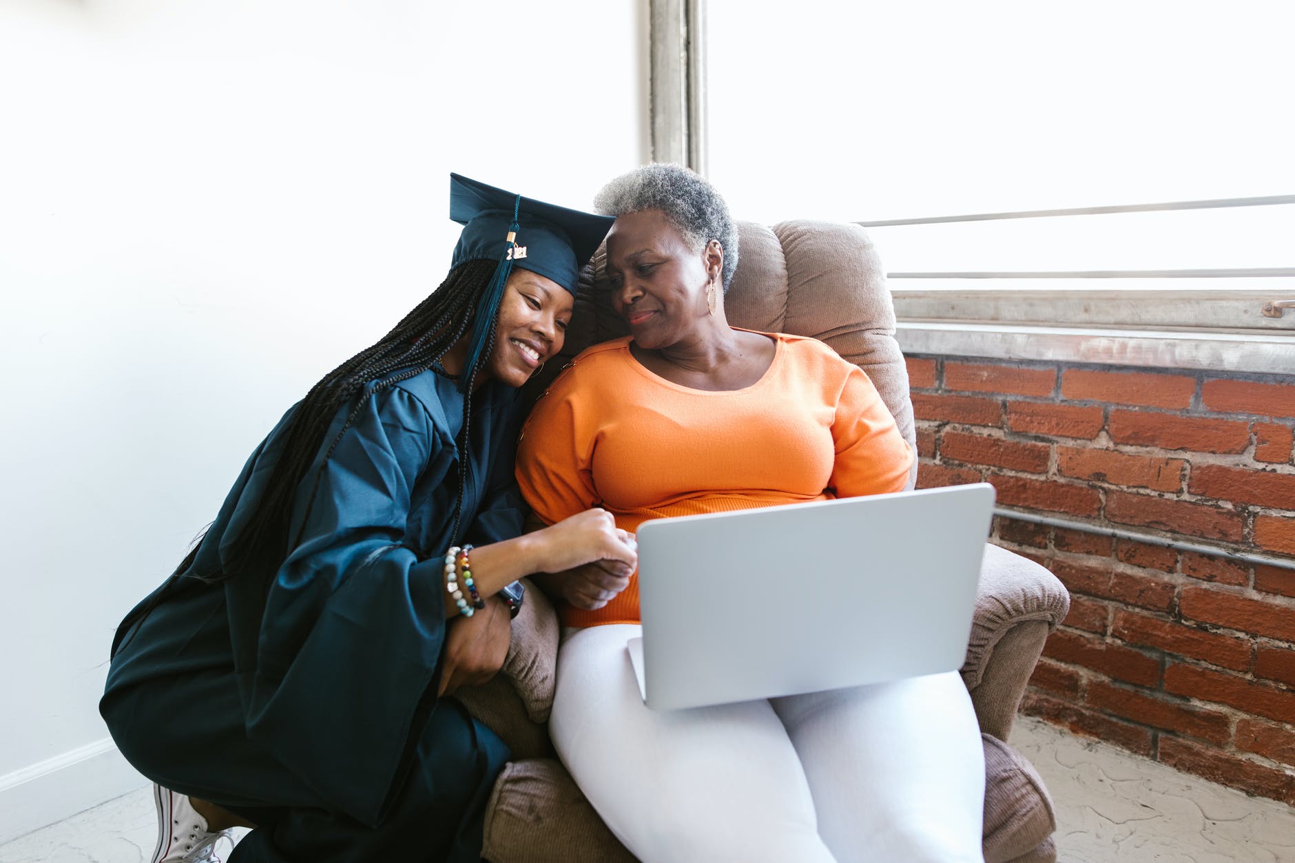 a woman in graduation dress sitting beside her mother