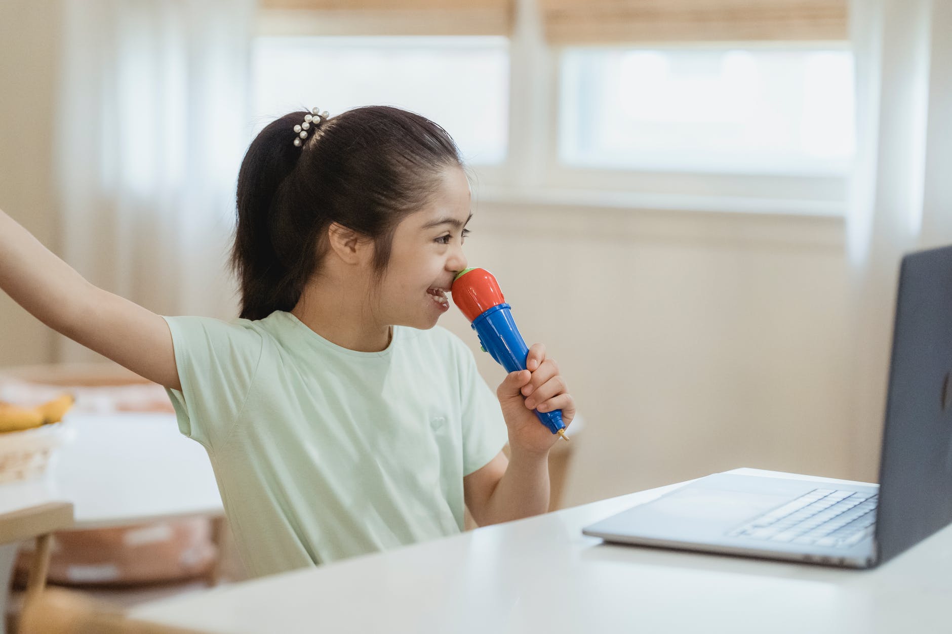 a young girl singing while looking at laptop