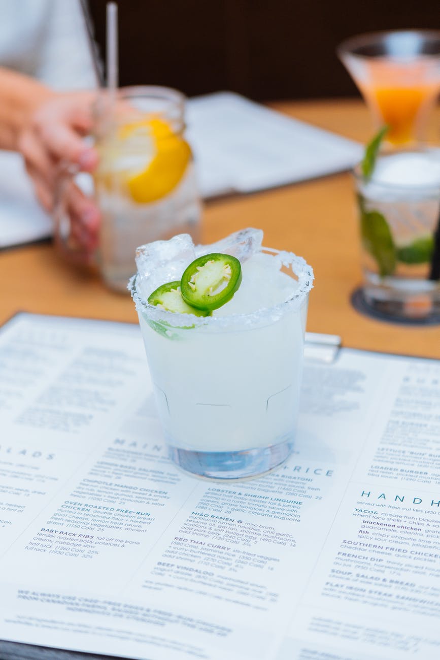 glass of tequila on top of a menu