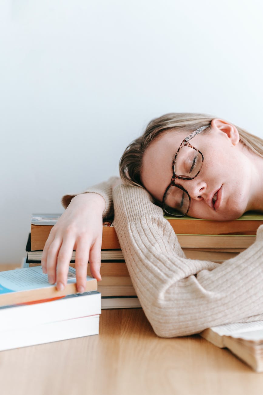 woman sleeping on books in room