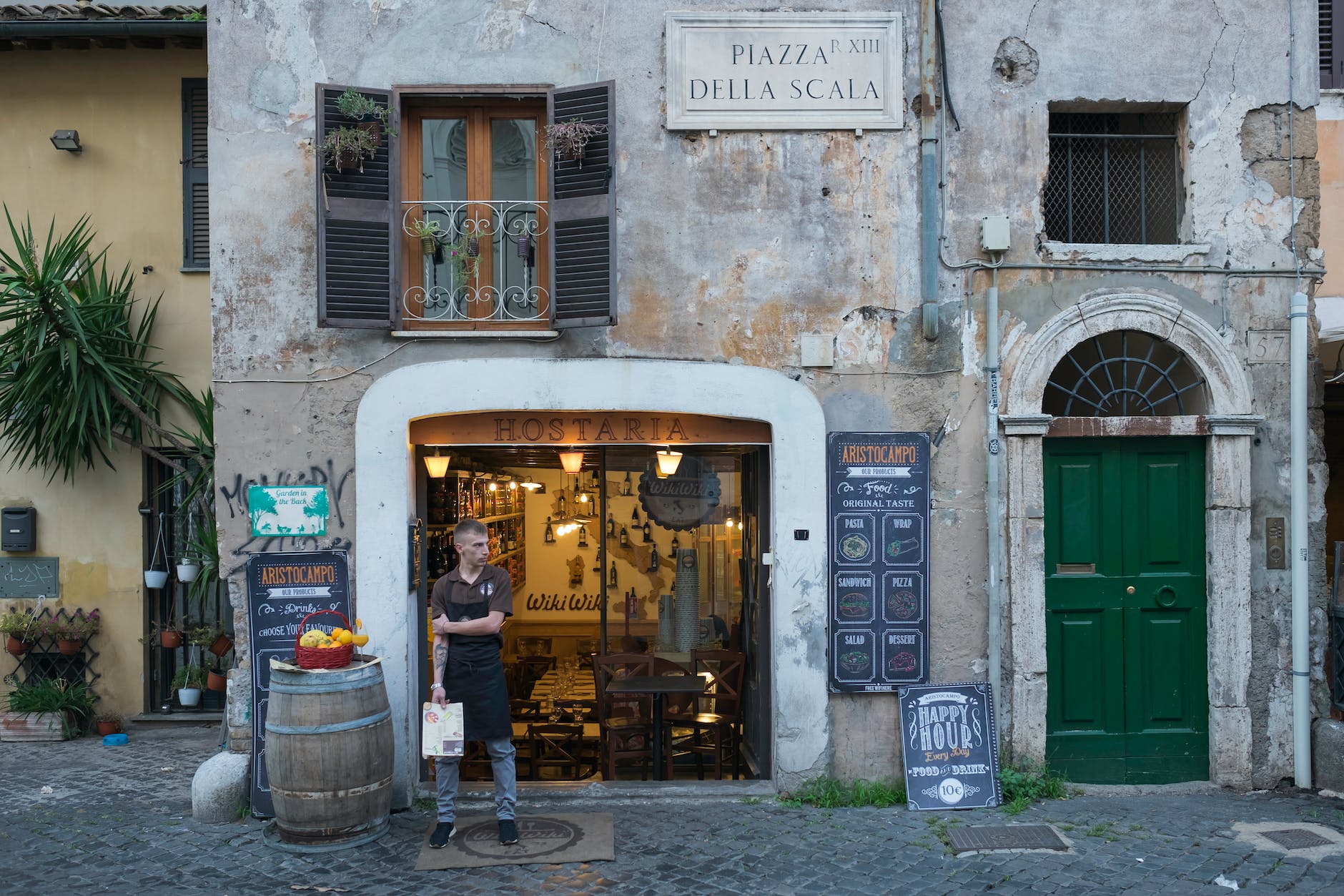a waiter standing outside the restaurant while holding a menu