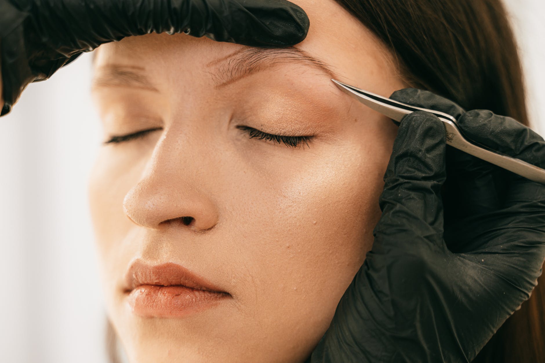 person plucking woman s eyebrow