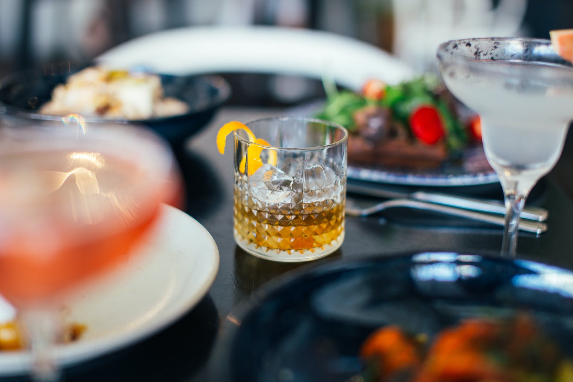 delicious cold cocktails and various dishes served on table in restaurant