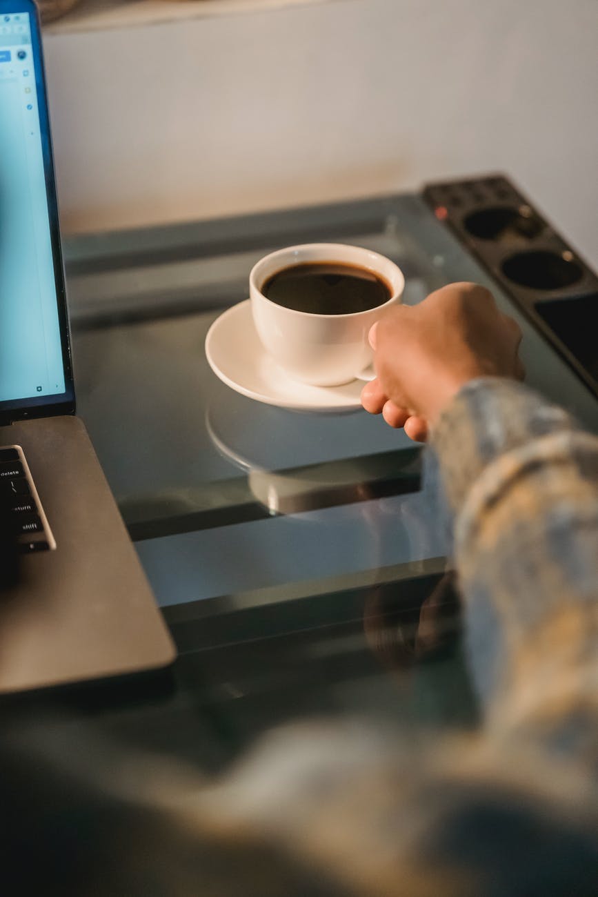 black man drinking coffee while working at laptop