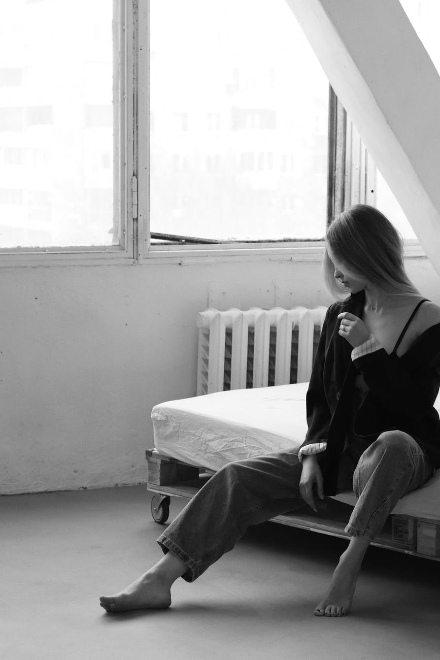 young sensitive woman sitting gracefully on bed