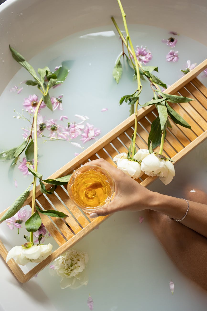 woman holding glass with wine while taking bath