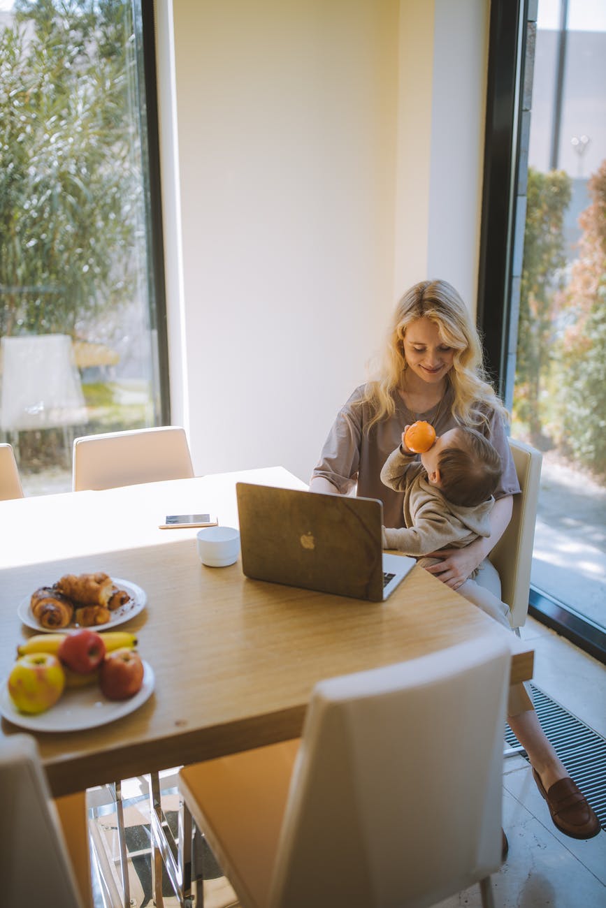 woman with her baby having breakfast and working