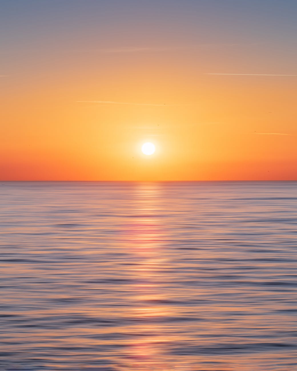 calm water with sun and orange sky