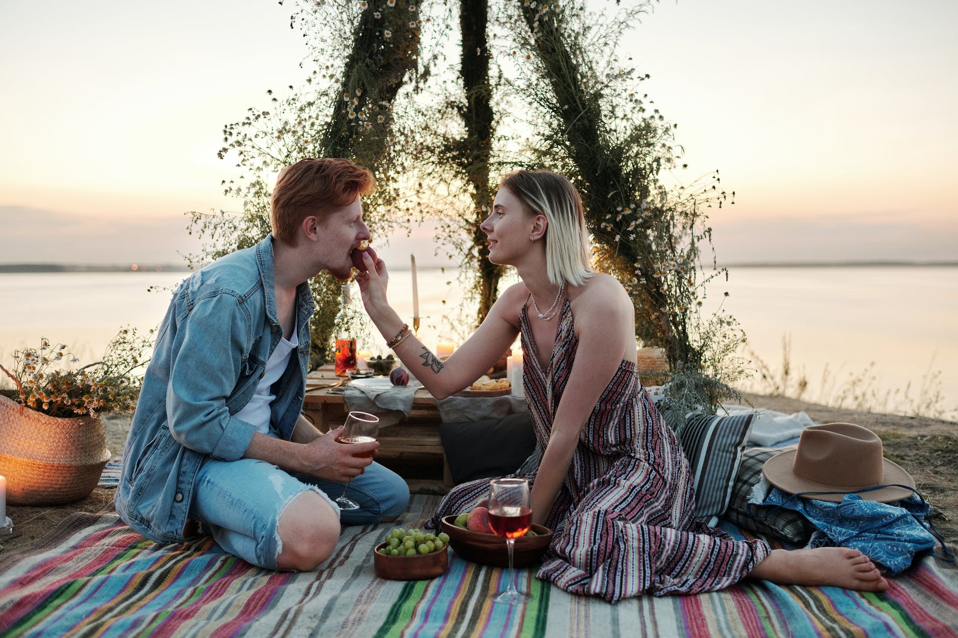 man and woman sitting on mat on beach