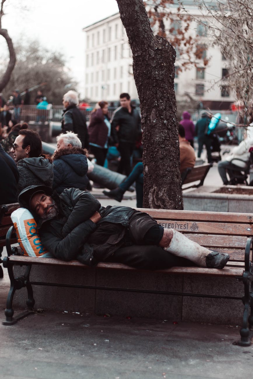 photo of man lying on wooden bench
