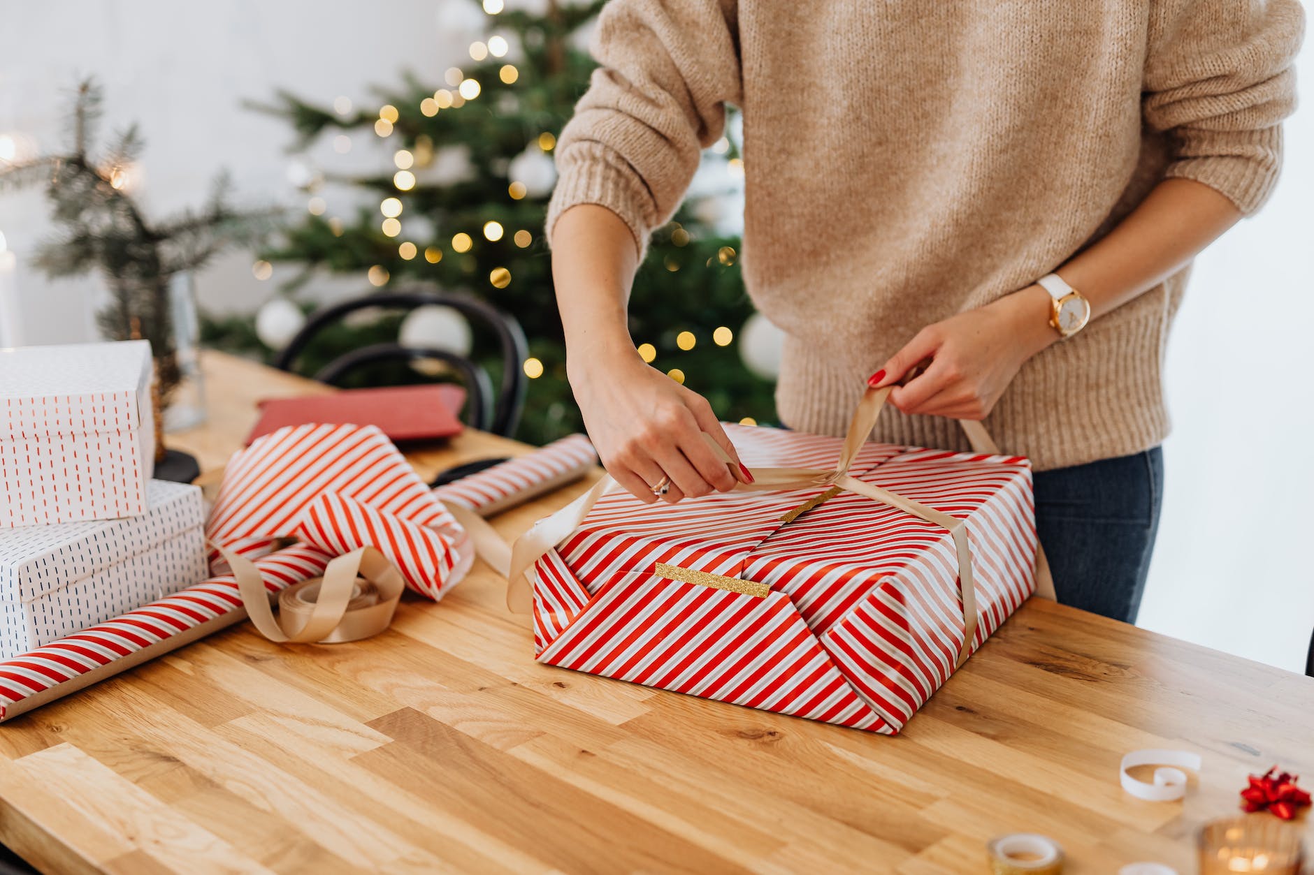 woman wrapping gift near christmas tree