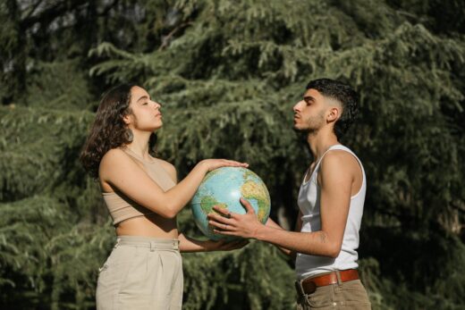 a man and a woman with eyes closed holding a globe